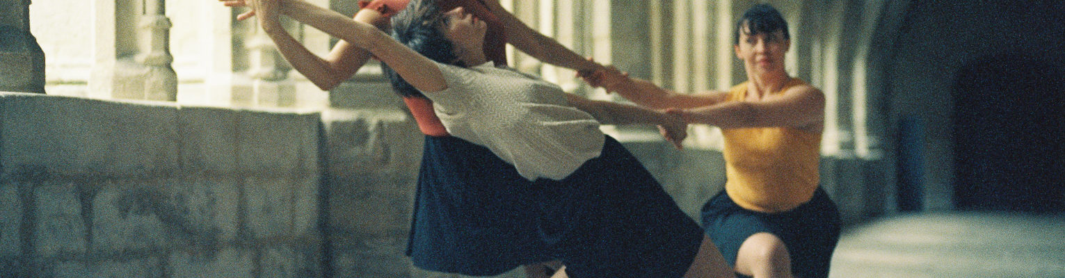 trois danseuses en action sous le passage couvert du cloître abbaye de la chaise dieu