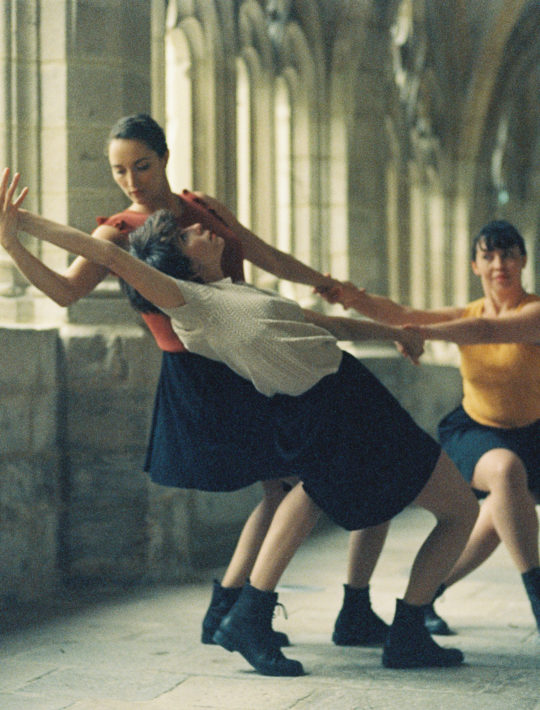 trois danseuses en action sous le passage couvert du cloître abbaye de la chaise dieu