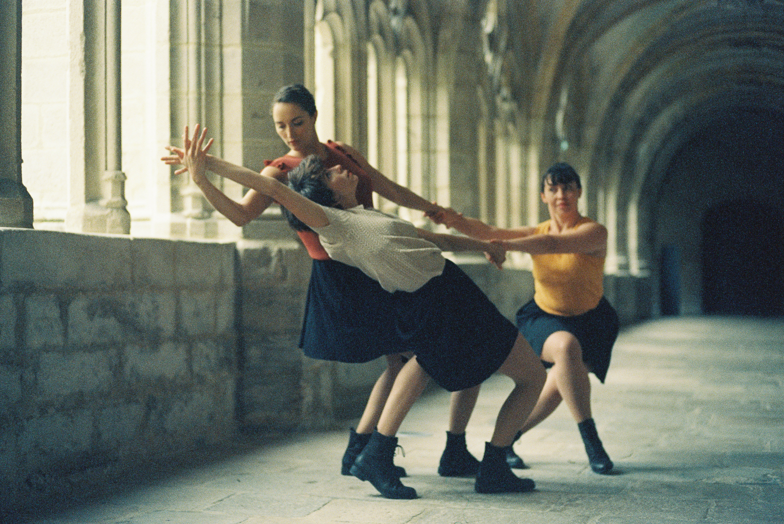 trois danseuses en action sous le passage couvert du cloître abbaye de la chaise dieu